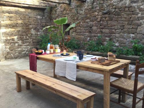 a wooden table and bench in front of a stone wall at EcoCamping d Hacadour in Mellionnec