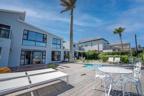 a patio with a table and chairs and a palm tree at The Lookout Guest House in Port Alfred