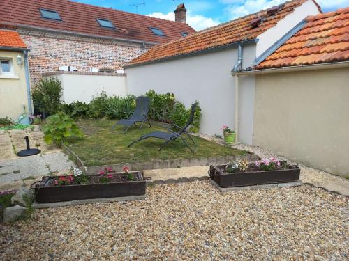 a garden with two plants and a chair in a yard at maison chaleureuse solognote mitoyenne in La Ferté-Saint-Aubin