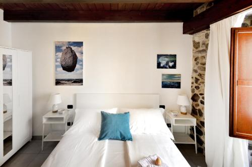 1 dormitorio con cama blanca y almohadas azules en Il sogno del pescatore, en Scilla