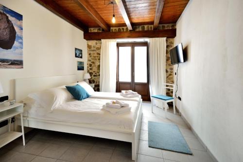 Schlafzimmer mit einem weißen Bett und einem TV in der Unterkunft Il sogno del pescatore in Scilla