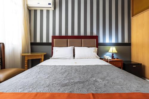 a bedroom with a bed and a striped wall at Recreo Hotel in Trujillo