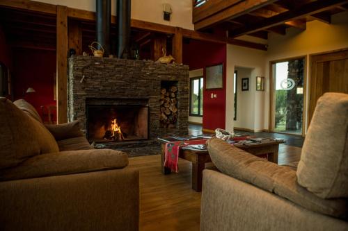 a living room with two couches and a fireplace at Lago Rosario Lodge in Trevelin