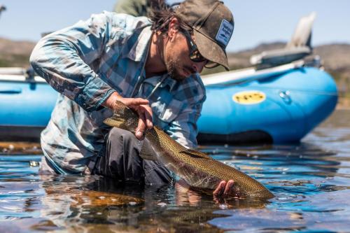 a man holding a fish in the water at Lago Rosario Lodge in Trevelin