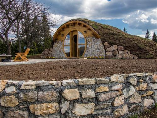 a stone wall in front of a building with a hill at Mountain bungalows and a Hobbit House - Jazavčije Rupe in Han Pijesak