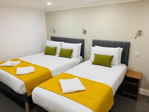 two beds in a room with yellow and white sheets at Park Avenue Bayswater Inn Hyde Park in London