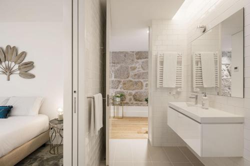 een witte badkamer met een wastafel en een bed bij The Downtown Charming Apartments in Porto