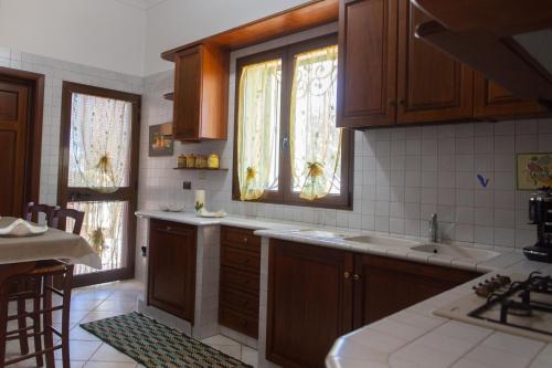 una cocina con armarios de madera, fregadero y ventanas en Villa Tonia, en Fasano