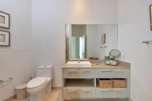 a bathroom with a sink and a toilet and a mirror at Penthouse Condo at Lyfe Resort and Residences in Hollywood