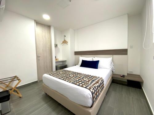 1 dormitorio con cama blanca grande y almohada azul en Seven Inn Hotel, en Medellín