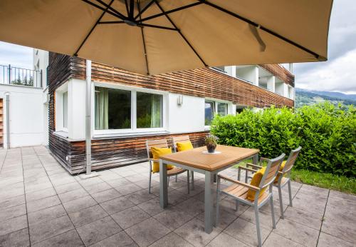 a patio with a table and chairs and an umbrella at Apartments Drei Türme by Pferd auf Wolke in Schruns-Tschagguns