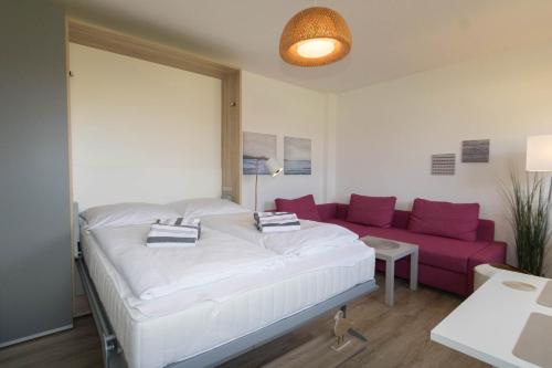 ヘルヌムにあるFerienwohnung Bartramのベッドルーム(大型ベッド1台、紫色のソファ付)