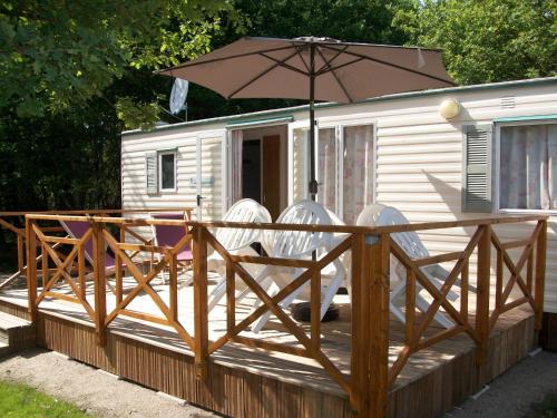a deck with two chairs and an umbrella at Mobilhome 2 calme et tranquilité in Vendays-Montalivet