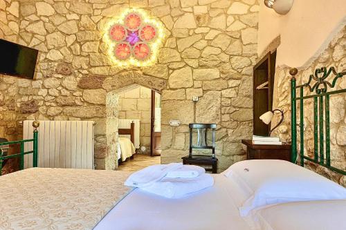 una camera con letto e parete in pietra di Masseria Casina Montana a Corigliano dʼOtranto