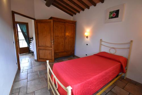 a bedroom with a red bed and a wooden cabinet at Falesta in Casole dʼElsa
