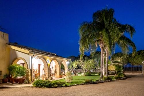 a palm tree in front of a house at night at Masseria Casina Montana in Corigliano dʼOtranto