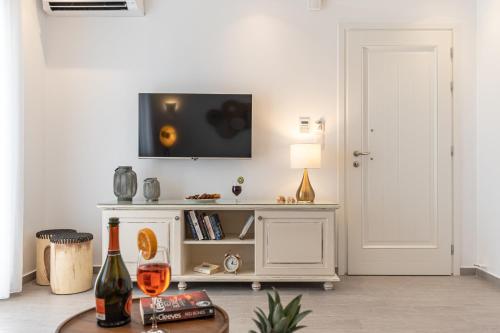 a living room with a tv on a white wall at Sea & Olives Suites Hotel and Villas in Plaka