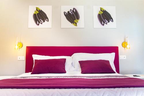 un letto con testiera rossa e tre immagini sul muro di ON' MICHELE GUEST HOUSE a Sorrento
