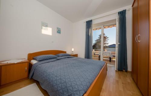 um quarto com uma cama com um edredão azul em Apartments Kordić em Rab