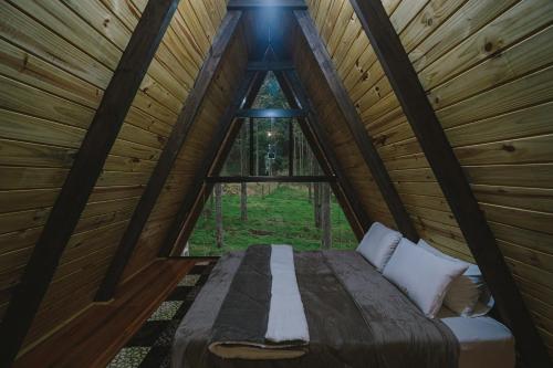 uma cama num quarto de madeira com uma janela em Cabanas do avencal em Urubici