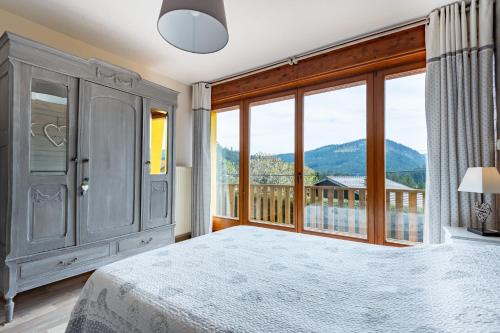 a bedroom with a bed and a large window at Le Repère Des Marmottes in Xonrupt-Longemer