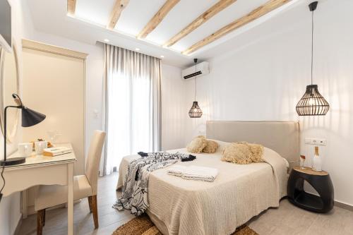 a white bedroom with a bed and a desk at Sea & Olives Suites Hotel and Villas in Plaka
