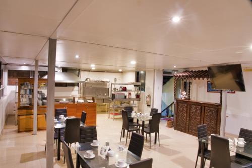una sala da pranzo con tavoli e sedie e una cucina di Hotel Rituales Inn - terminal terrestre a Cuzco