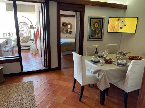 a dining room with a table with white chairs at Lovely 2 bedroom with a pool in front of the beach in Sesimbra
