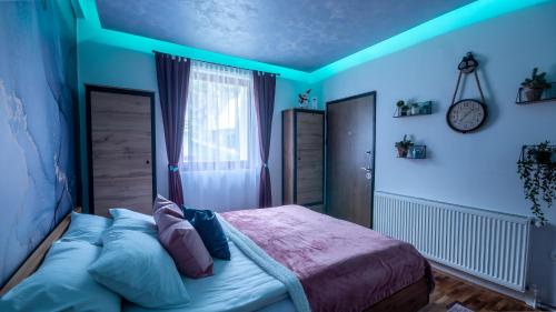Schlafzimmer mit blauen Wänden, einem Bett und einem Fenster in der Unterkunft Alpin Apartments Vlašić in Vlasic