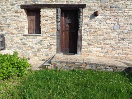 a brick building with a wooden door in the grass at Chalet Euthalia Restaurant & Suites in San Giacomo