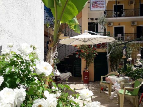 a patio with a table and an umbrella and flowers at Art Studios Benitses in Benitses