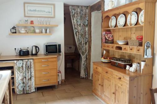 une cuisine avec des armoires en bois et des assiettes sur les étagères dans l'établissement Tranquil rustique gite couples only pres Rochefort en Terre, à Limerzel