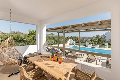 a patio with a table and chairs and a swimming pool at Sea & Olives Suites Hotel and Villas in Plaka