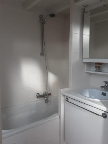 La salle de bains blanche est pourvue d'une douche et d'un lavabo. dans l'établissement Sixtyfour penthouse, à Knokke-Heist