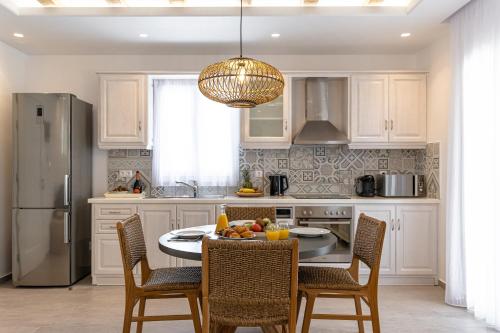 a kitchen with a table and chairs and a refrigerator at Sea & Olives Suites Hotel and Villas in Plaka