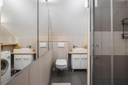 een badkamer met een toilet, 2 wastafels en een wasmachine bij Apartament Via Regia in Krościenko