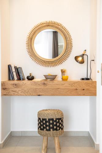 a mirror on a counter with a rattan chair at Sea & Olives Suites Hotel and Villas in Plaka