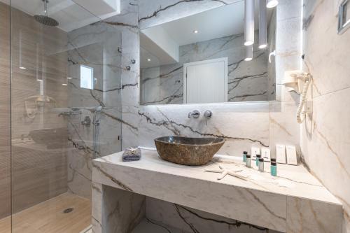 a bathroom with a sink and a large mirror at Sea & Olives Suites Hotel and Villas in Plaka