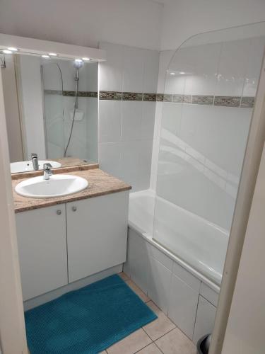 une salle de bain blanche avec un lavabo et une douche dans l'établissement Résidence calme avec piscine, à Béziers