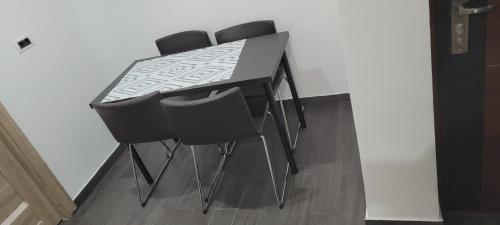 une table de salle à manger noire avec quatre chaises noires dans l'établissement ANDI 2-apartament, à Băile Herculane