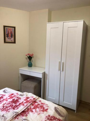 a bedroom with a white cabinet and a bed with pink flowers at Апартамент 10 in Tsarevo