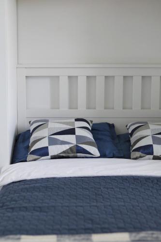 a bed with blue and white pillows on it at Capital Towers - Apartament Modern w centrum miasta z widokiem na rzekę i park in Rzeszów