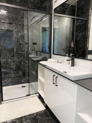 a bathroom with a white sink and a shower at Capital Towers - Apartament Modern w centrum miasta z widokiem na rzekę i park in Rzeszów