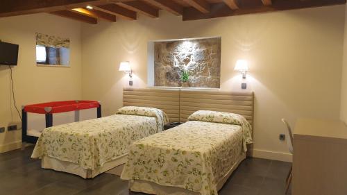 Habitación con 2 camas y una pintura en la pared. en Casa Rural Rectoral Santa Baia, en Boimorto