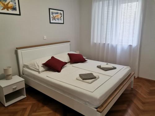 a bedroom with a large white bed with red pillows at Apartman Mihaela in Rab