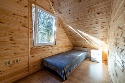 a bed in a log cabin with a window at Oleandria Domek z kominkiem in Biskupiec