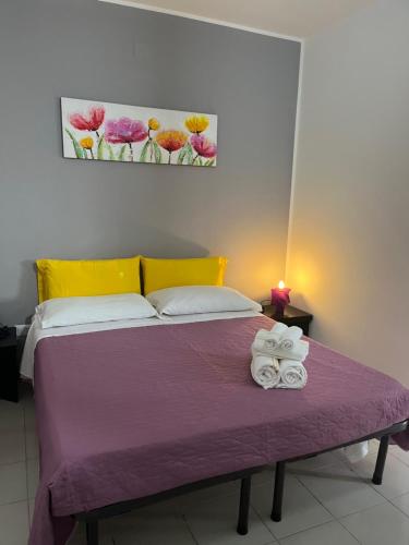 um quarto com uma cama roxa com toalhas em monolocale 2 LudoLeo 5p em Quartu SantʼElena