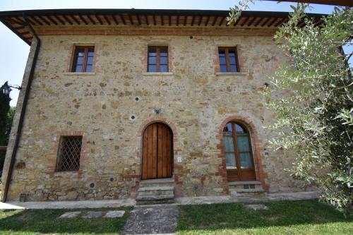 an old stone house with a wooden door at Falesta in Casole dʼElsa