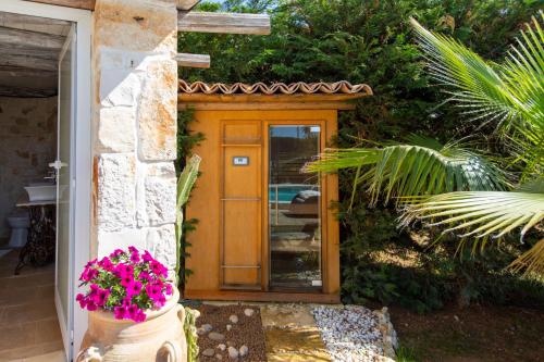 a wooden door on a house with pink flowers at Villa Letto D'Alloro - Royal Dream in Conversano
