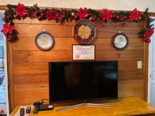 a television on a table with three clocks on a wall at M&M Residence in Baguio
